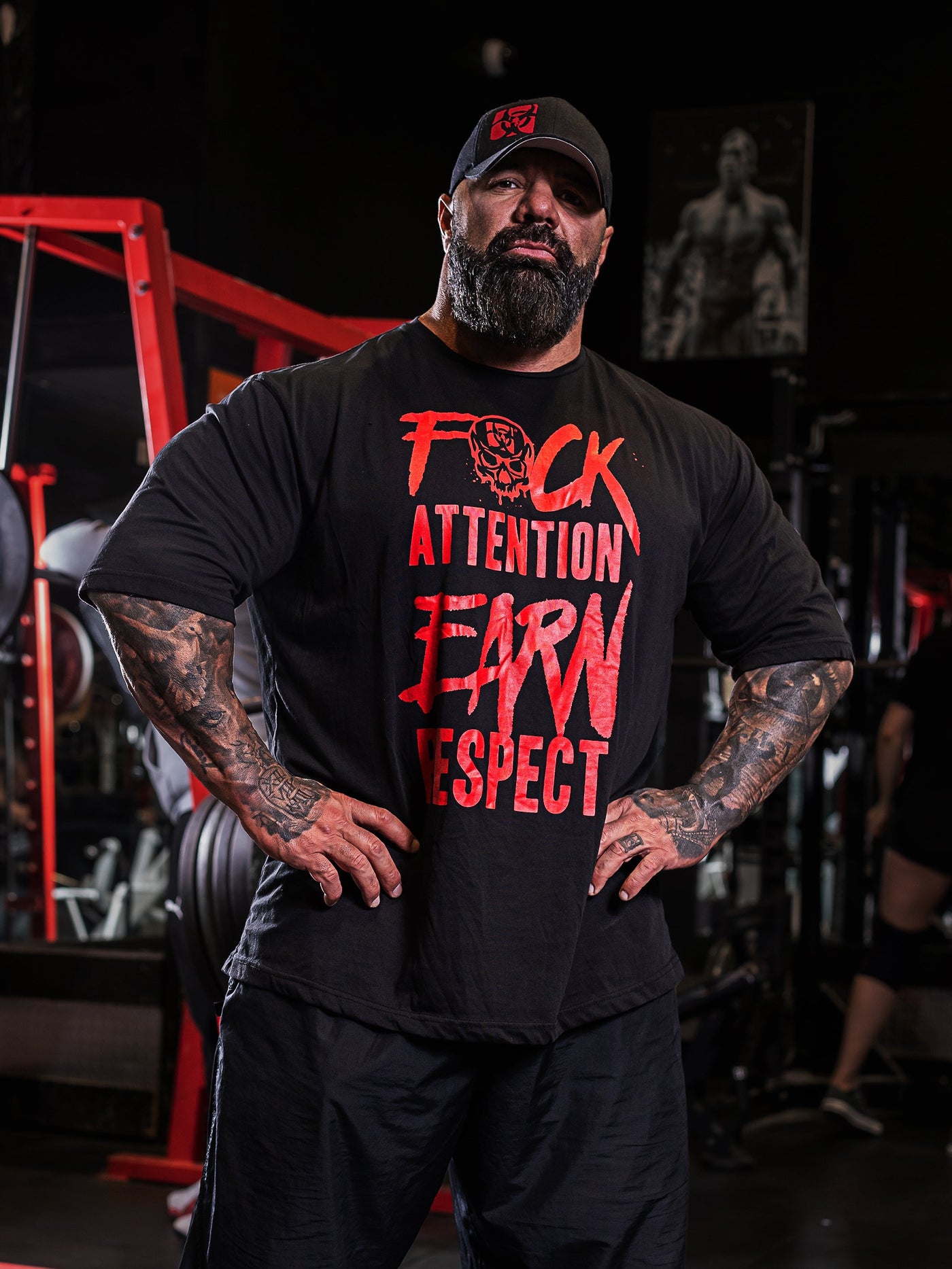 Dusty Hanshaw, Mutant athlete, posing in the gym wearing the Black 'Dusty Says' Mutant Oversized Gym T-shirt with his motto 'F*ck attention earn respect' in red.